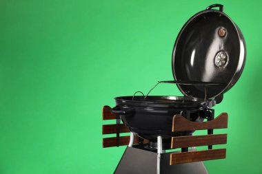 One black barbeque grill against green background. Space for text clipart