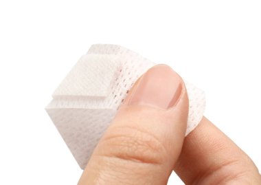 Kadın, beyaz arka plana tıbbi yapıştırıcı bandaj yapıştırıyor. Yakın plan.