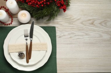 Tabaklar, çatal bıçak takımı ve ahşap masa üzerindeki şenlikli Noel sofrası düz yatıyordu. Metin için boşluk