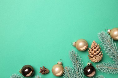 Noel dekoru. Firavun ağacı dalları, koniler ve turkuaz arka planda takılar, düz bir zemin. Metin için boşluk