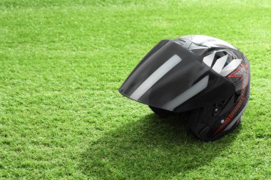 Yeşil çimlerin üzerinde güneşliği olan modern motosiklet kaskı, metin için alan