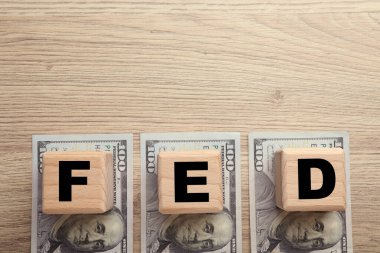 Fed (Federal Rezerv Sistemi) harfli küpler ve ahşap masa üzerinde dolar banknotları, düz yatıyordu. Metin için boşluk