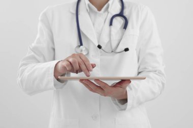 Beyaz arkaplanda tableti olan doktor, yakın plan görünümü