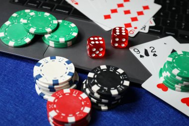 Poker fişleri, dizüstü bilgisayar, mavi masada kağıt ve zarlar. Çevrimiçi oyun