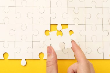 Sarı arka planda beyaz bulmacayı çözen kadın, yakın plan