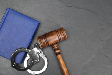 Kitap, yargıç tokmağı ve kelepçe gri desenli masa, düz yatak. Metin için boşluk