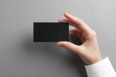 Gri arka planda boş kartviziti olan bir kadın, yakın plan. Tasarım için model
