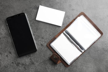 Deri kart tutucu, boş kartvizitleri ve gri desenli masasında akıllı telefonları var. Tasarım için model