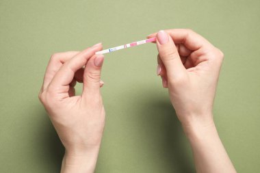 Zeytin arka planında hamilelik testi tutan kadın, üst görünüm