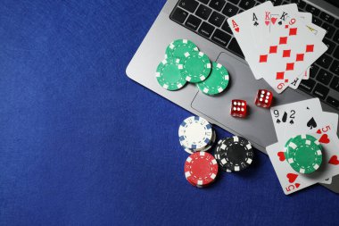 Çevrimiçi oyun. Poker fişleri, dizüstü bilgisayar, kağıt ve zarlar mavi masada, düz konum. Metin için boşluk