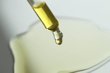 Gerekli petrolü gri arka planda pipetten damlatıyor, yakın plan