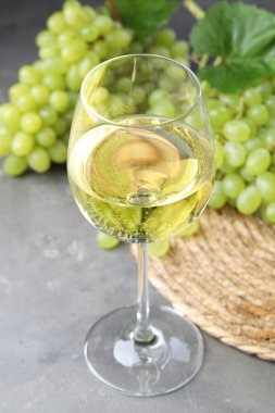 Taze üzümler ve gri masada bir bardak şarap.