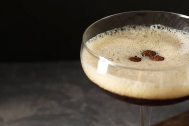 Bulanık arka planda kahve çekirdekli enfes espresso martini, yakın plan. Metin için boşluk