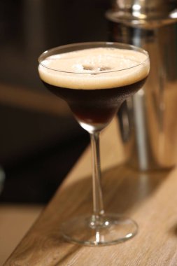 Bardaki ahşap masada nefis espresso martinisi, yakın plan.