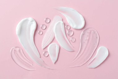 Pembe arka planda farklı kozmetik ürünlerinin kokusu.