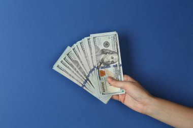 Mavi arka planda dolar banknotları olan kadın, yakın plan.