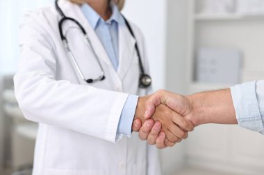 Hastanedeki hastayla el sıkışan doktor, yakın plan.