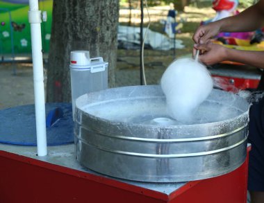 Man making cotton candy with machine outdoors, closeup