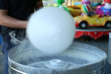 Man making cotton candy with machine outdoors, closeup