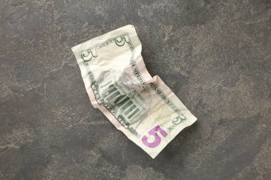 Gri masanın üstünde buruşmuş bir dolar banknot.