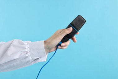 Açık mavi arka planda mikrofonu olan kadın, yakın plan.