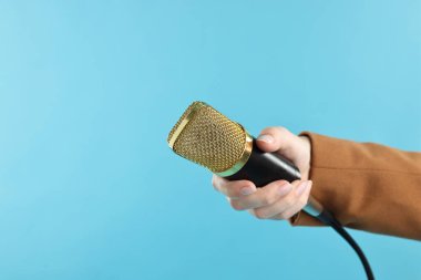 Açık mavi arka planda mikrofonu olan kadın, yakın plan.