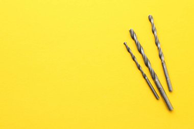 Sarı arka planda farklı matkap uçları, üst manzara. Metin için boşluk