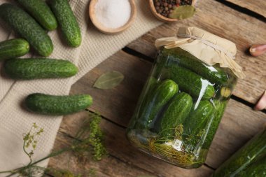 Kavanozda salatalık turşusu, ahşap masada dereotu ve baharat.