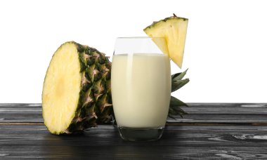 Bardakta lezzetli ananas püresi ve beyaz arka planda tahta masada meyve dilimleri.