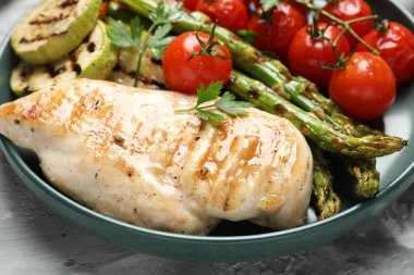 Lezzetli ızgara sebzeler ve tavuk göğsü masada, yakın plan.