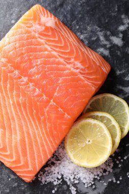 Koyu masada taze somon, limon ve tuz var.