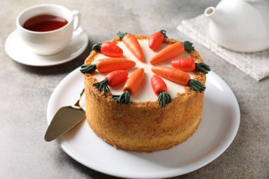 Lezzetli havuçlu kek, sunucu ve çay gri masada.