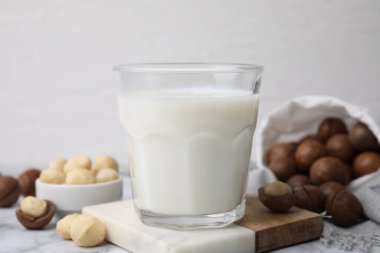 Beyaz mermer masada bir bardak Macadamia sütü ve fındık, yakın plan.