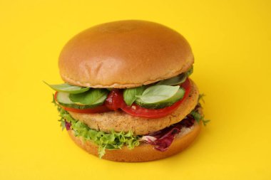 Sarı arka planda nohut pirzolası ile nefis vegan burger, yakın plan.