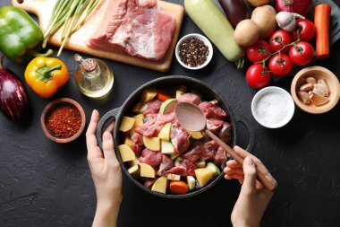 Yemek pişirme güveci. Pişmemiş eti, sebzesi ve tenceresi olan bir kadın.