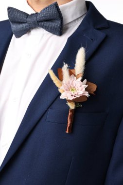 Beyaz arka planda şık yaka çiçekleri olan damat, yakın plan.