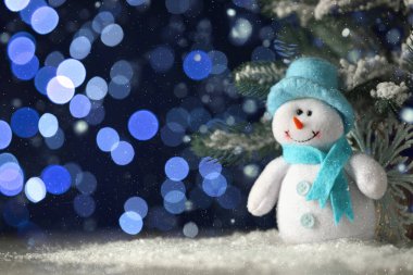 Tatlı kardan adam koyu mavi arka plana karşı bulanık Noel ışıkları, bokeh etkisi. Metin için boşluk