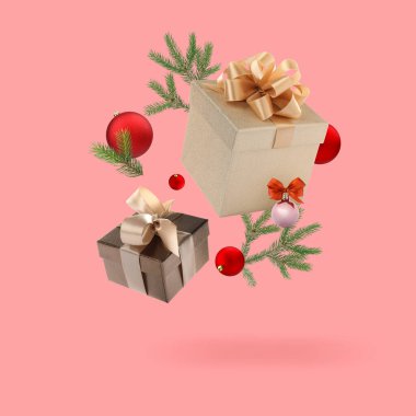Hediye kutuları, Noel baloları ve pembe arka planda havada köknar dalları