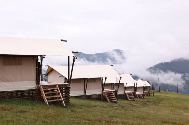 Dağlarda sisle kaplı bir sürü çadır ve orman var. Glamping alanı