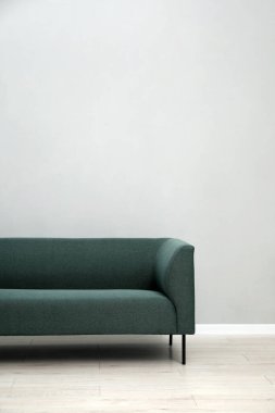 Açık gri duvarın yanındaki rahat kanepe kapalı, metin için yer var.