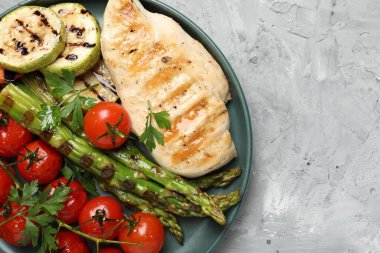 Açık gri desenli masada nefis ızgara sebzeler ve tavuk göğsü, üst manzara. Metin için boşluk