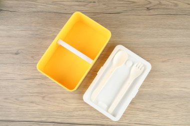 Boş plastik beslenme çantası, çatal bıçak takımı, ahşap masa, üst manzara.