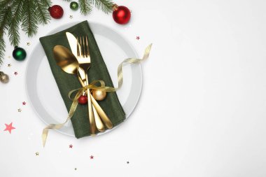 Beyaz arka planda tabak, çatal bıçak, peçete ve şenlik dekoruyla Noel sofrası. Metin için boşluk