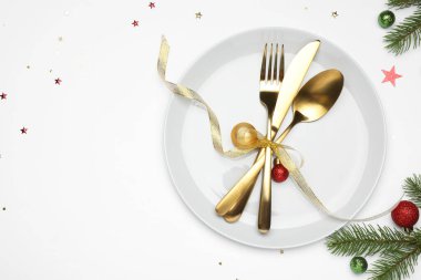 Beyaz arka planda tabak, çatal bıçak takımı ve şenlik dekoruyla Noel sofrası. Metin için boşluk