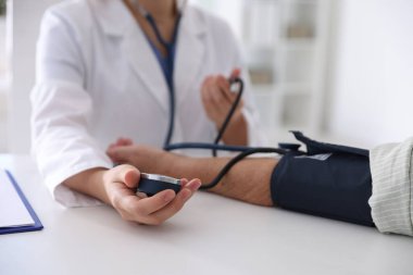 Hastanedeki masada hastanın kan basıncını ölçen doktor, yakın plan.