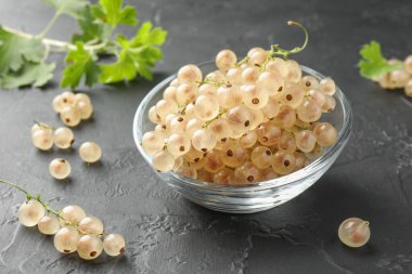 Kasede taze kuşüzümü ve gri desenli masada yeşil yapraklar, yakın plan.