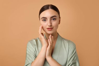 Bej arka planda sağlıklı cilde sahip güzel genç bir kadın.