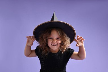 Cadılar Bayramı için cadı gibi giyinmiş komik kız menekşe arka planda