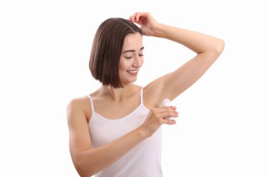 Gülümseyen kadın beyaz arka plana deodorant sürüyor.