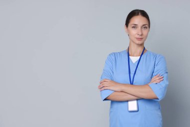 Gri arka planda rozeti olan hemşire, mesaj için yer var.